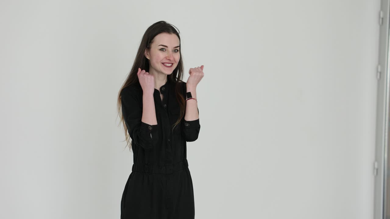 Woman in black jumpsuit celebrating indoors