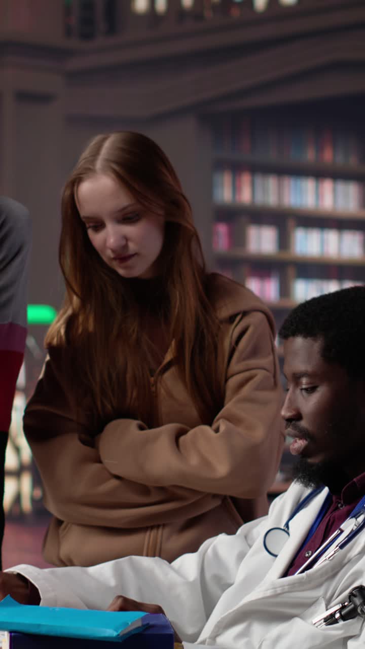 Vertical video multiethnic group of students in a library participate at a lesson with doctor