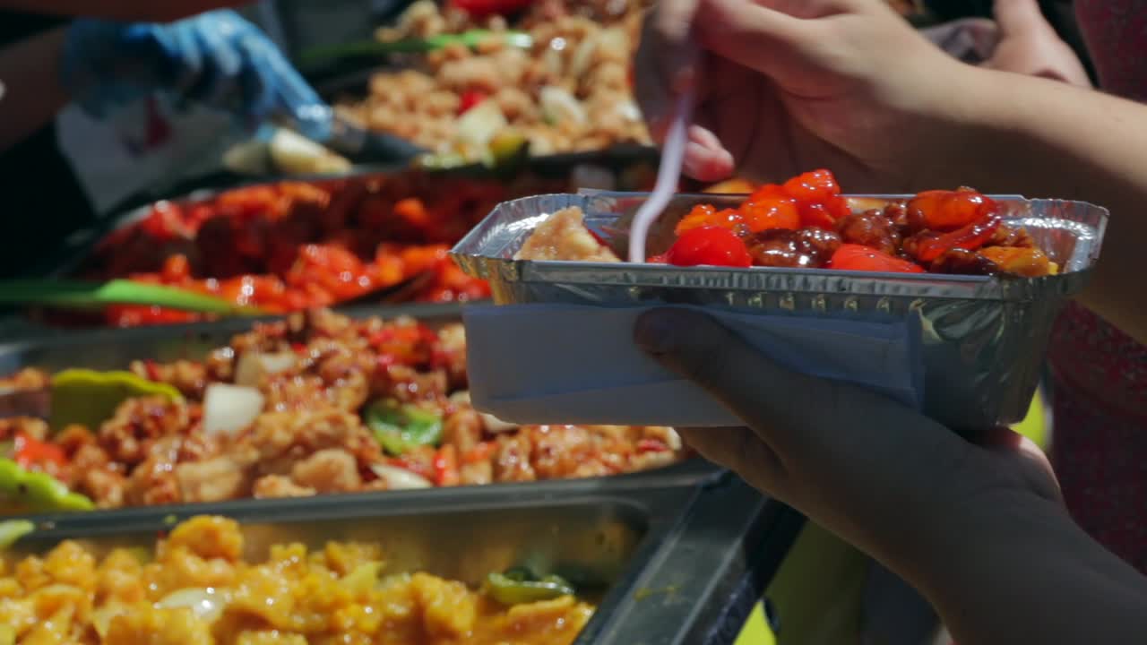 Eating asian cuisine at a street food stall using a white plastic fork.