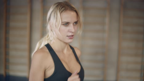 portrait of serious woman training on running machine in sport club.