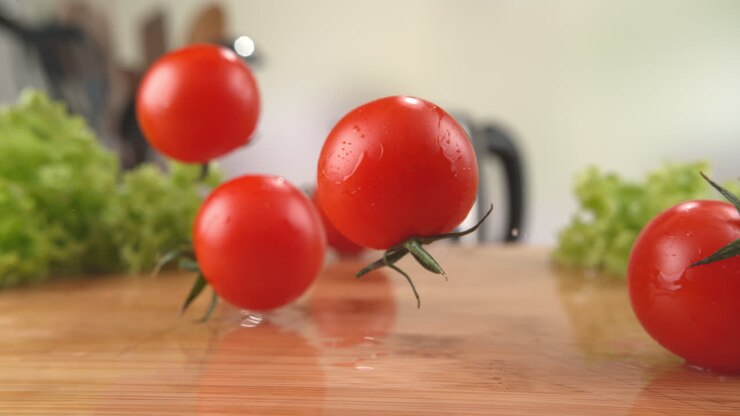 Ripe Cherry Tomatoes Falling Onto The Wooden Kitchen Table, Bouncing And Splashing Water Droplets Around in Macro and Slow Motion