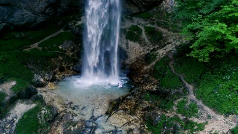 man with beard is doing waterfall-meditation under big waterfall