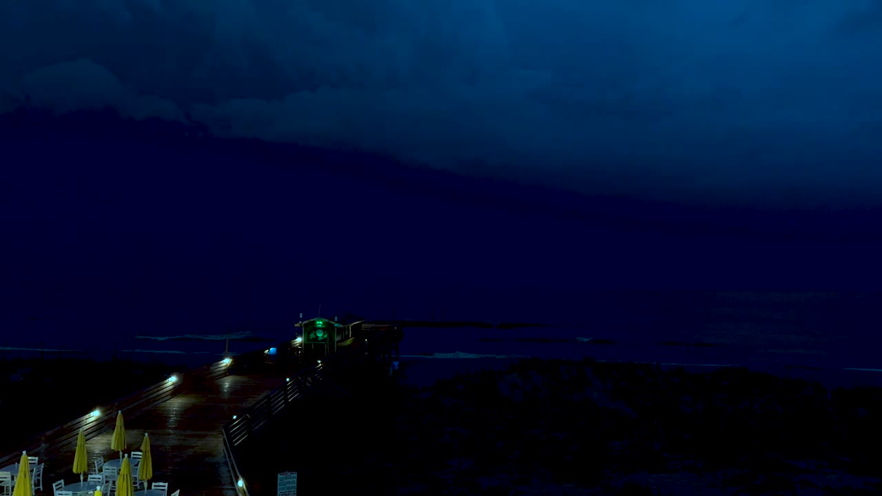 Thunder and lightning during a spring storm on the beach with a pier in the foreground