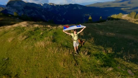 fpv footage was filmed in the slovenian mountain village in the alps with a drone flying fast over mountains filmed with a gopro with incredible surrounding landscapes with a hiker holding a flag