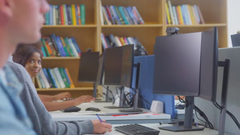 Estudiante-Universitaria-O-Universitaria-Que-Trabaja-En-Una-Computadora-En-La-Biblioteca-Siendo-Ayudada-Por-Un-Tutor