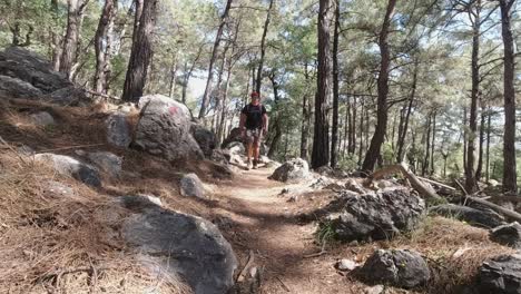 man with backpack hiking in middle of rocky mountainous forest in lycian way, turkey