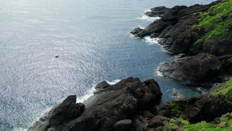 stunning aerial orbit of island coastline and lagoon with jagged boulders and vast ocean waters