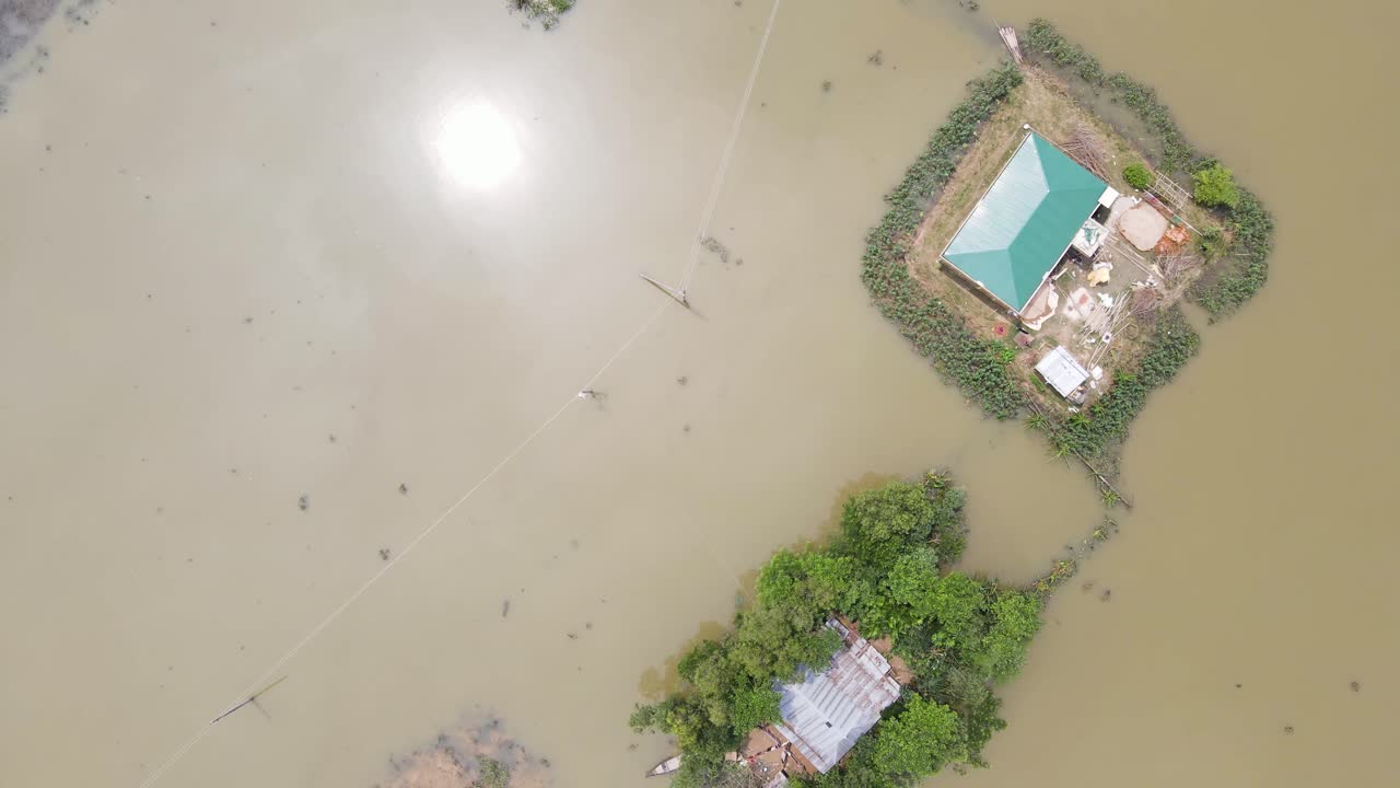 Flood affected village with house surrounded by floodwater in Bangladesh. Aerial top down shot