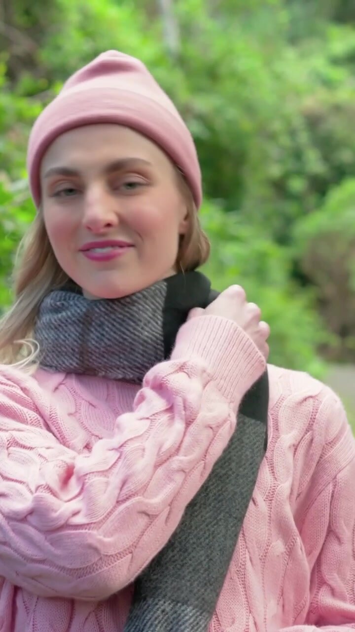 Video verticale: Si sistema dopo un primo piano, donna con maglia rosa e cappello che si aggiusta la sciarpa su un sentiero per la telecamera
