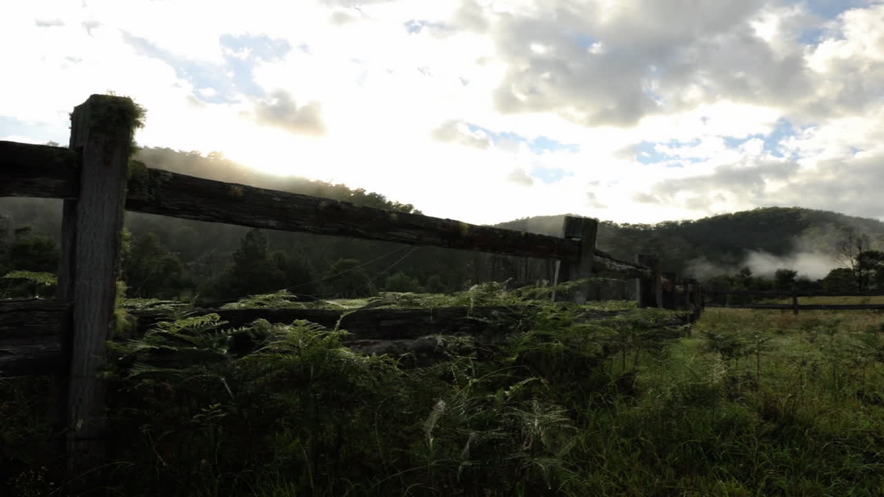 나무 울타리가 있는 초원 위로 흩어지는 구름의 시간 경과