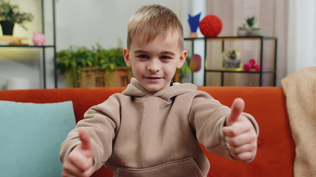 Happy child kid boy looking approvingly at camera showing thumbs up like positive sign good news