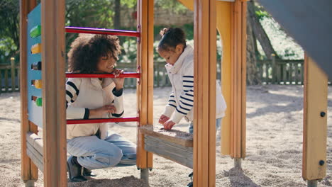 mujer buscando juego de hija de pie en el patio de recreo. mamá disfrutando del tiempo juntos