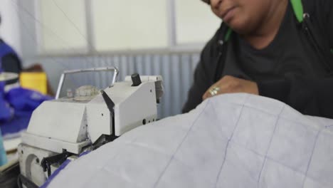 mixed race woman using sewing machine in factory