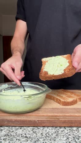 Man spreading homemade avocado cream on toast