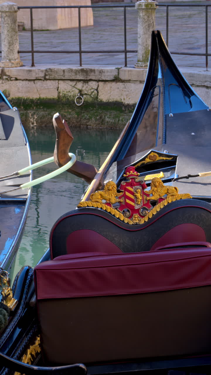 Gondolas docked on the side of a canal in Venice, Italy. Vertical