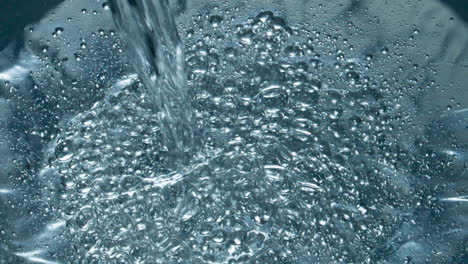 soda blebs floating on the aqua surface closeup. fizzy drink jet filling vessel