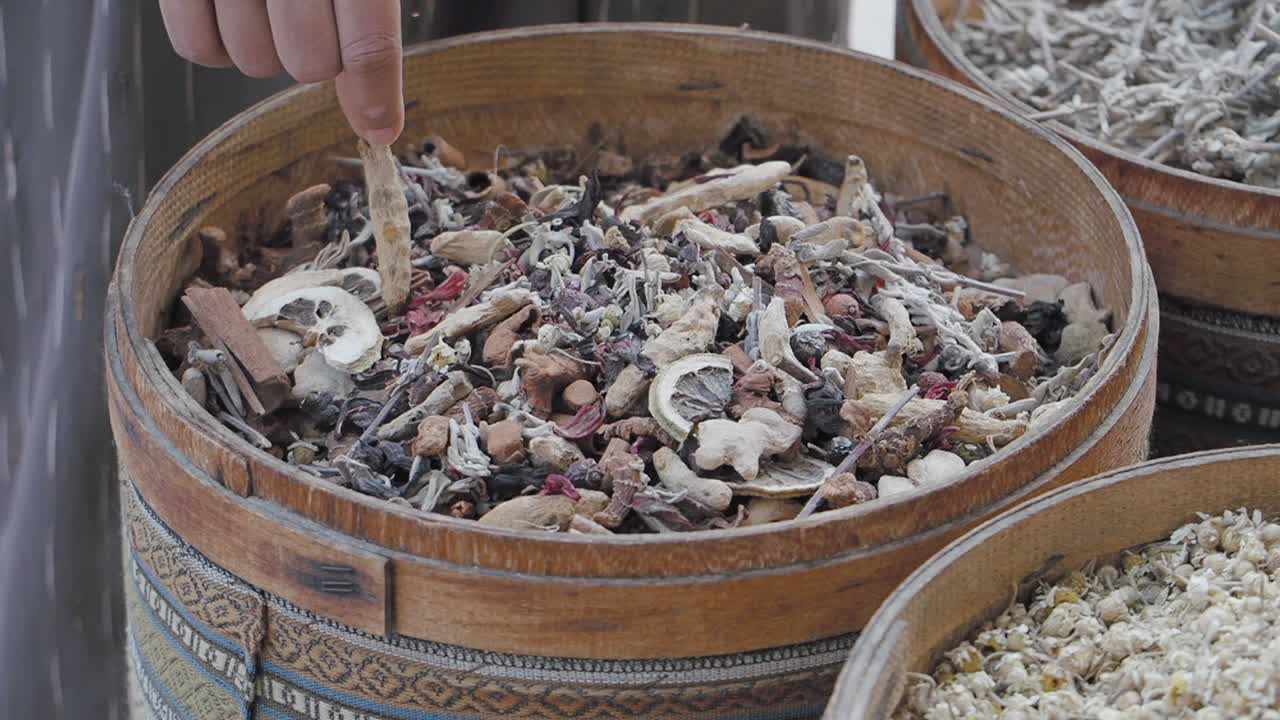 Hand Selecting Dried Herbs and Spices from Wooden Basket