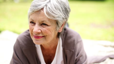 Happy-senior-woman-relaxing-in-the-park-thinking