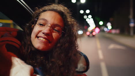 portrait of teenager girl sitting in car outside window looking through at night city road street