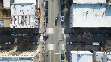 Toma-De-Seguimiento-De-Arriba-Hacia-Abajo-De-Un-Automóvil-Negro-Conduciendo-En-Las-Calles-De-La-Ciudad-De-Nueva-York-El-Día-De-La-Primavera