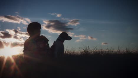 4k outdoor silhouette of child and dog watching the sunset
