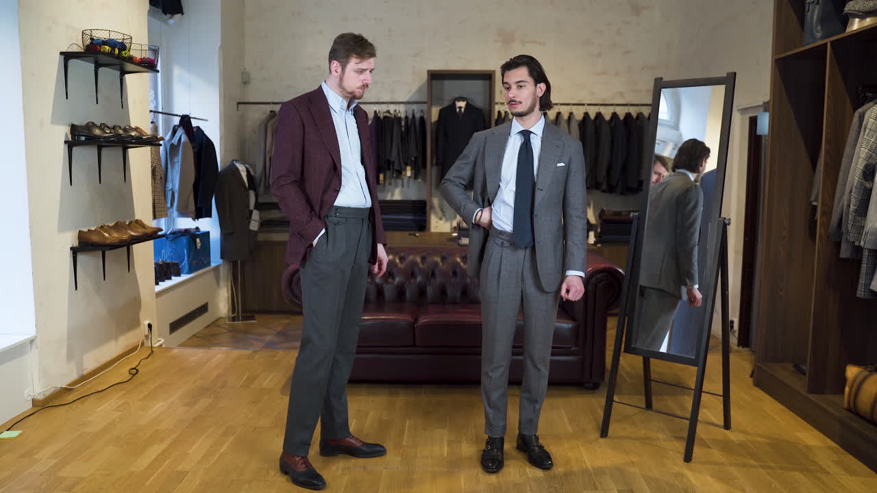 Cliente explicando al asistente de la boutique cómo le sienta el traje nuevo durante la prueba.