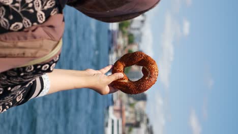 hand holding a simit over water