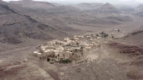 a drone shot of an old middle eastern town between mountains with a bazaar full of people