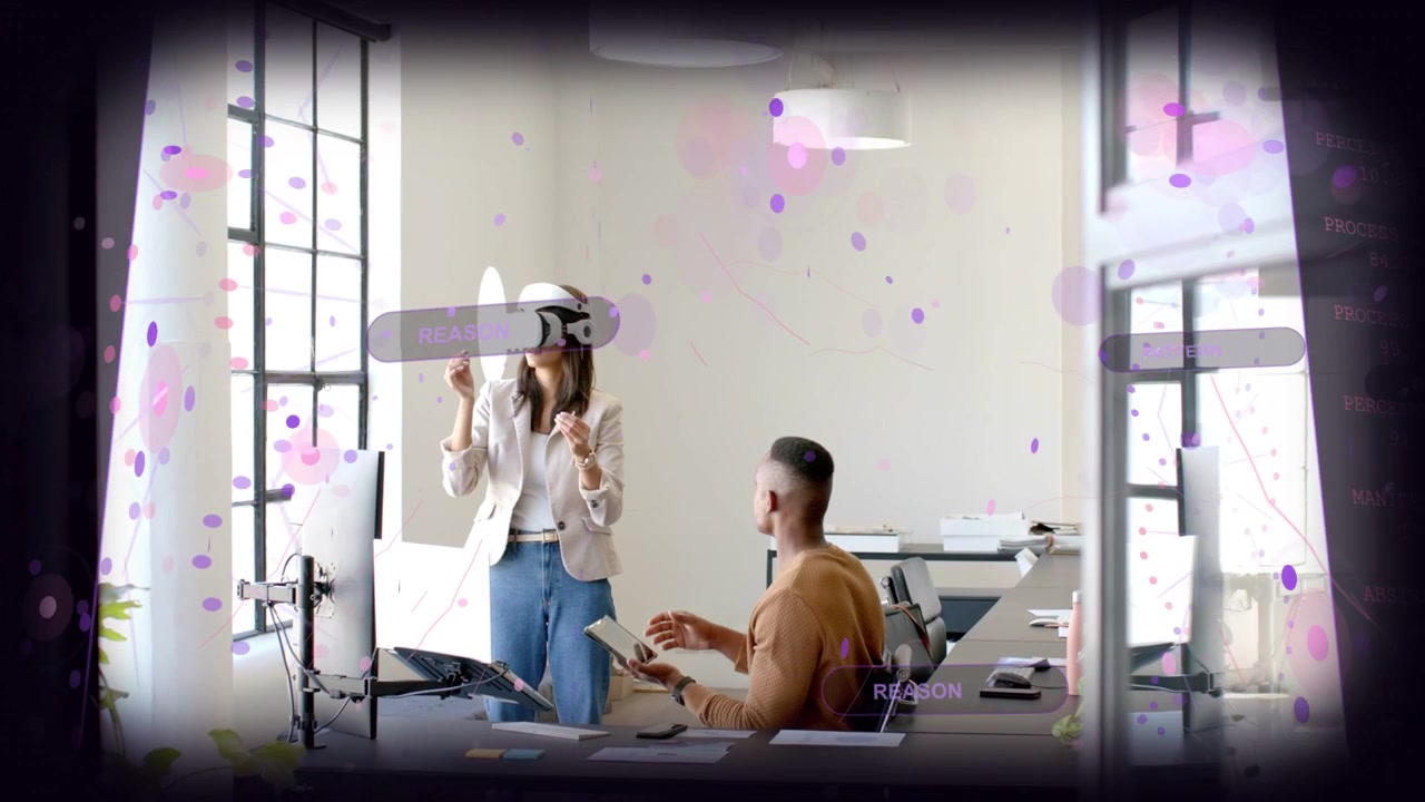 Donna che regola un visore VR e manipola un'interfaccia utente olografica mentre un uomo seduto tocca un tablet per una demo tecnologica.