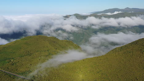 aerial panorama, madeira island ridge with lush green vegetation and low clouds on sunny summer day, drone shot