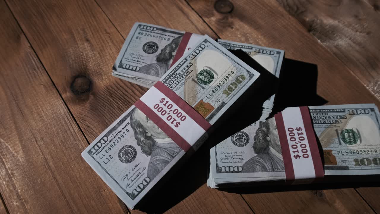 Three Stacks of 10000 American Dollars Banknotes in Bundles Lie on Wooden Table