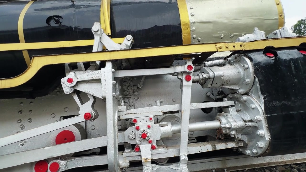Panning close up of the mechanical running gear and connecting rods on a preserved steam locomotive displayed outdoors Editorial use only