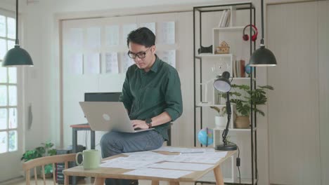 creative designer sits on his desk holds laptop on the knees and working on the project . creative design and gaming content development studio