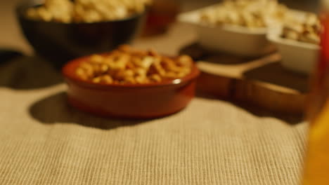 close up of hand choosing from bowls of cashews dry roasted peanuts and pistachio nuts in studio 3