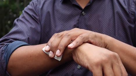 man disinfecting his hands with a wet wipe