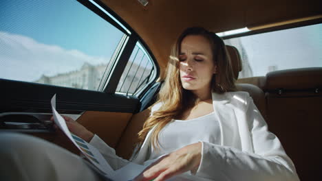 focused business woman looking into data in documents in comfortable modern car.