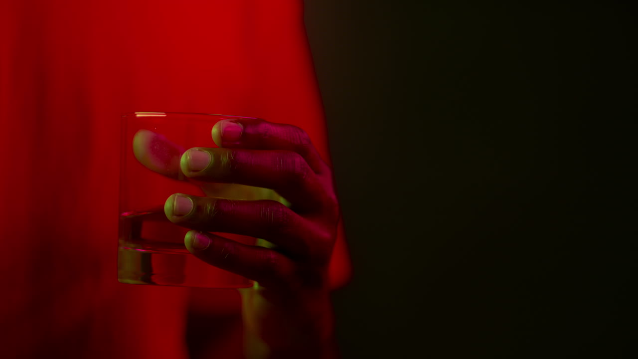 Mano che regge un bicchiere alla luce al neon