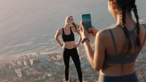 girl friends taking photo on mountain top using smartphone camera beautiful young woman posing for friend with mobile phone sharing hiking adventure on social media