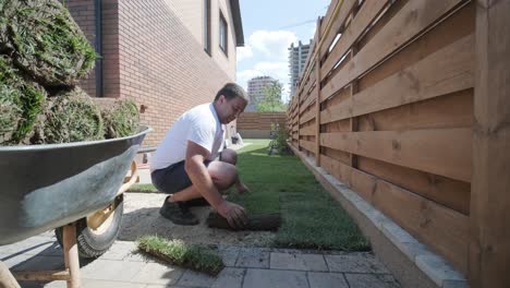 jardinero colocando césped en el patio privado con valla de madera