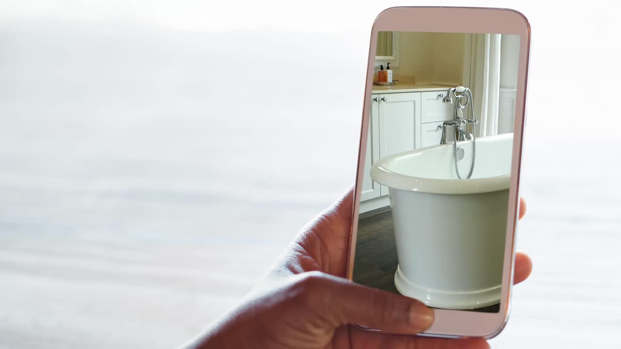 스크린에 표시된 현대적인 욕실 인테리어와 함께 스마트 폰을 들고 있는 사람