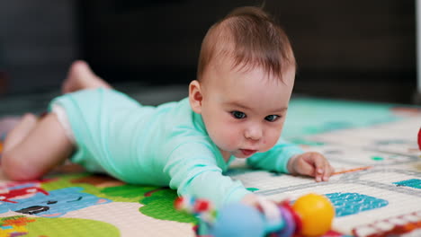 sweetest child in blue outfit tries to reach his toy. funny toddler takes a toy and shakes it. blurred background.