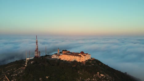 Foggy-sunrise-flying-over-Monte-Toro-in-Menorca,-Spain