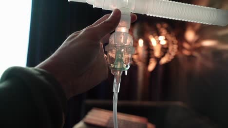 one hand holding nebulizer assembly with liquid medication in nebulizer chamber