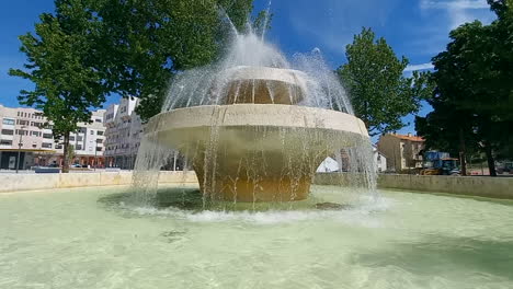 fountain with several fountains of crystal clear water and trees around it in a city space