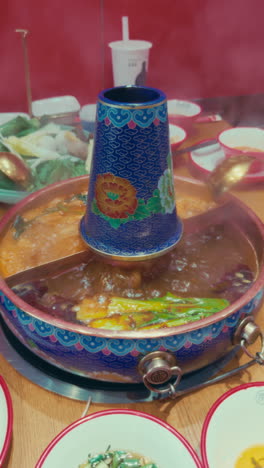 steaming hot pot with a colorful traditional design, served in wuzhen, china.