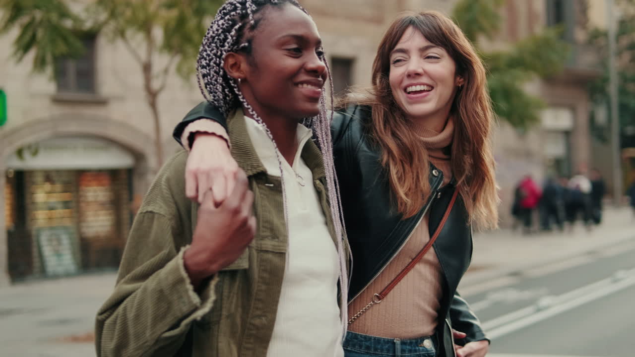 Two Happy Multi-Ethnic Female Friends Walking and Laughing on a City Street