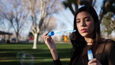 close up of a happy young woman smiling with joy blowing bubbles in the dreamy outdoor sunlight