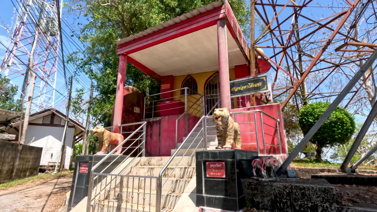 Camera moves toward red shrine with lion statues, bright daylight, outdoor setting, clear sky