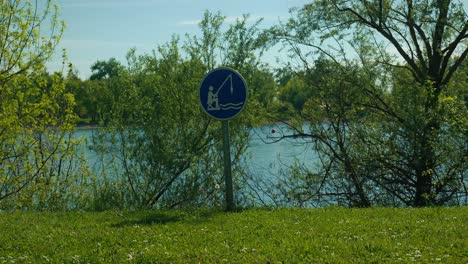 tranquila orilla del lago con señal de pesca permitida en medio de una vegetación vibrante en el lago jarun, zagreb, croacia