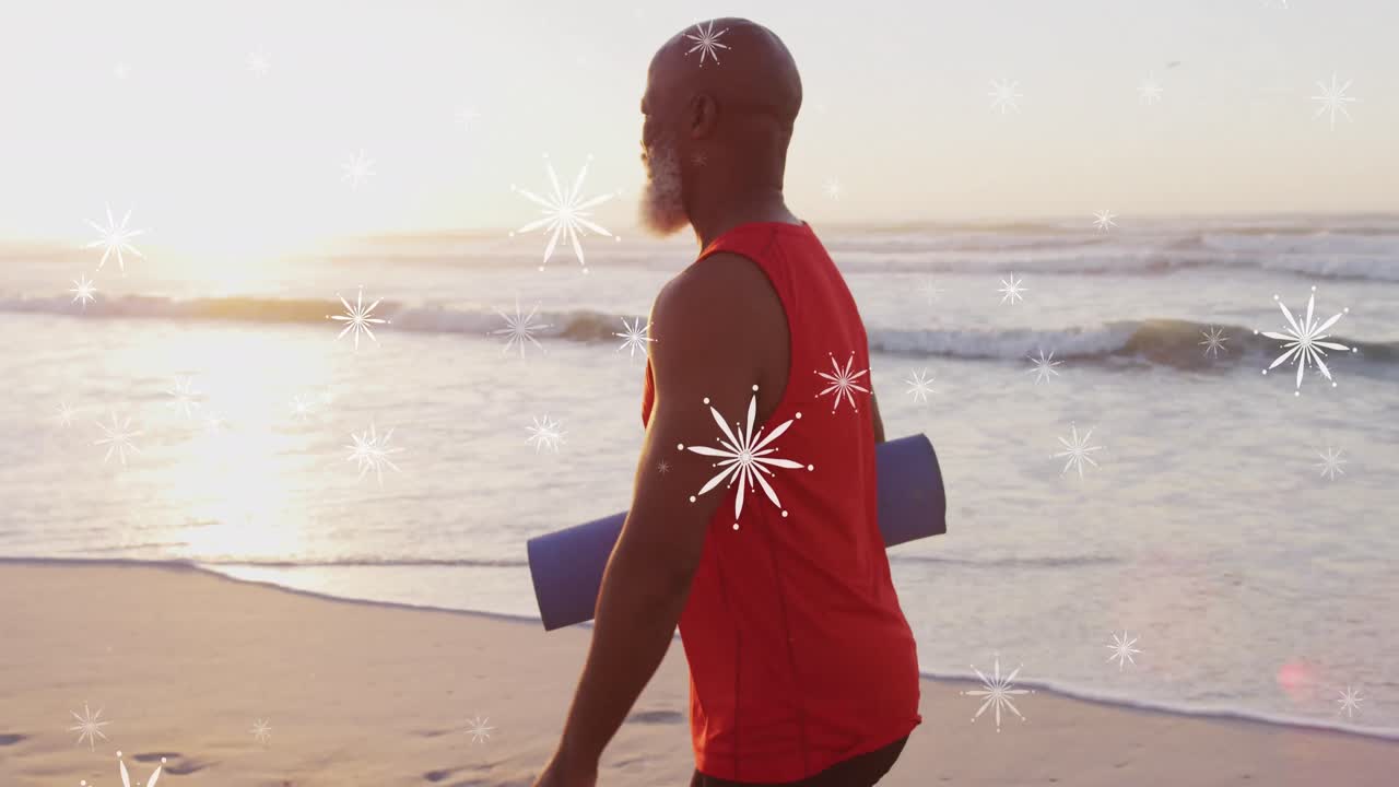 Animation of christmas snow falling over senior african american man on beach